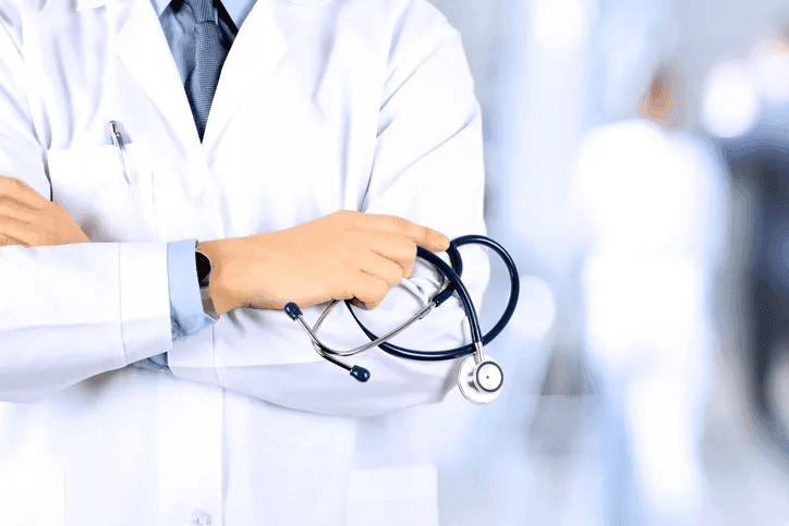 Doctor in white coat holding a stethoscope with arms crossed.